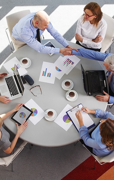 Team collaborating at a round table with laptops and charts
