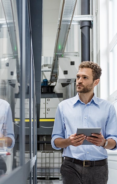 Engineer using a tablet in an industrial facility with machinery.