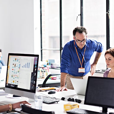 Office team discussing project with computer screens displaying data