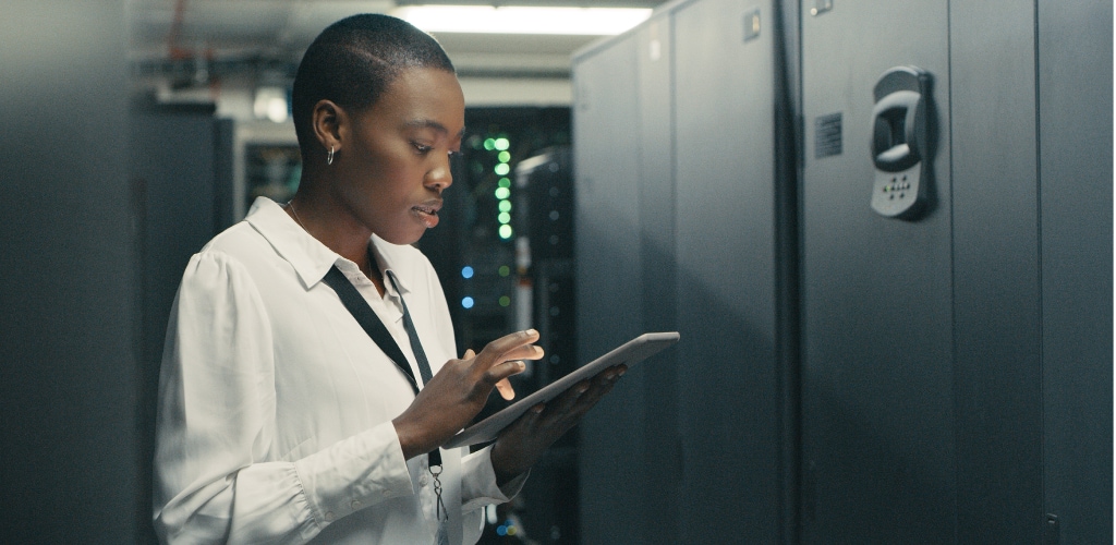 Woman engineer using a tablet in a server room with equipment.