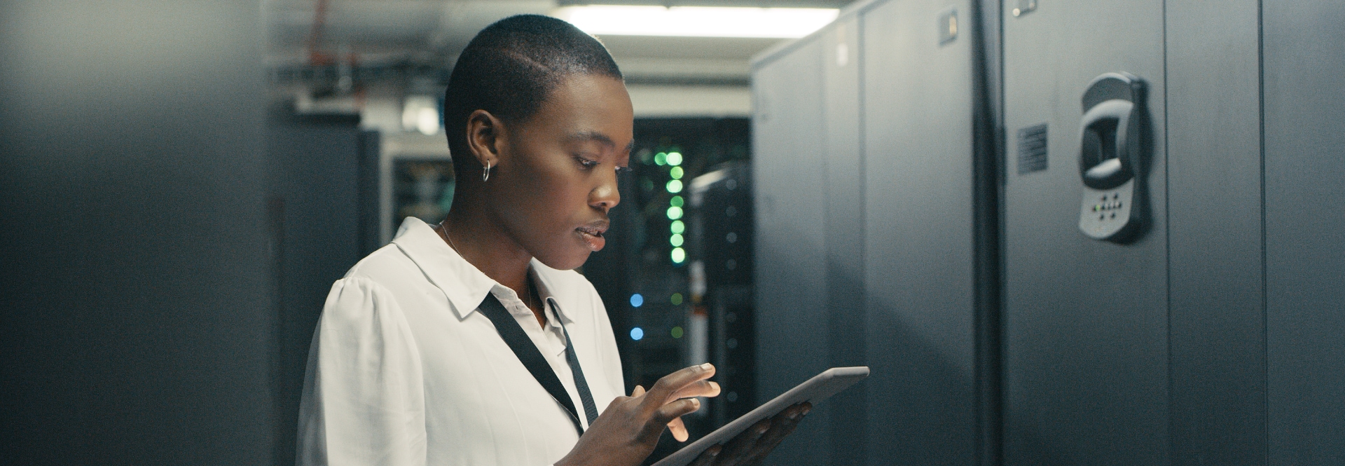 Woman engineer using a tablet in a server room with equipment.
