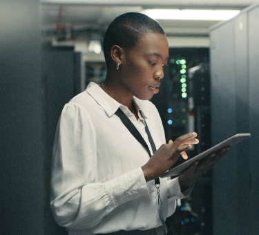 Woman engineer using a tablet in a server room with equipment.