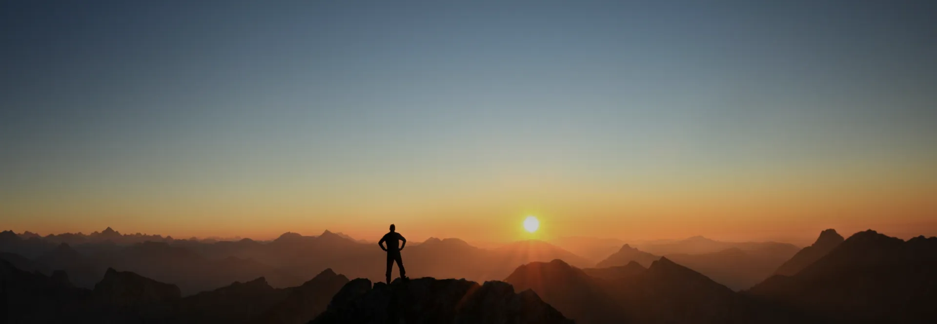 日出时站在山顶上的人