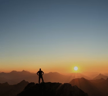 A man on top of the mountains during a sunrise