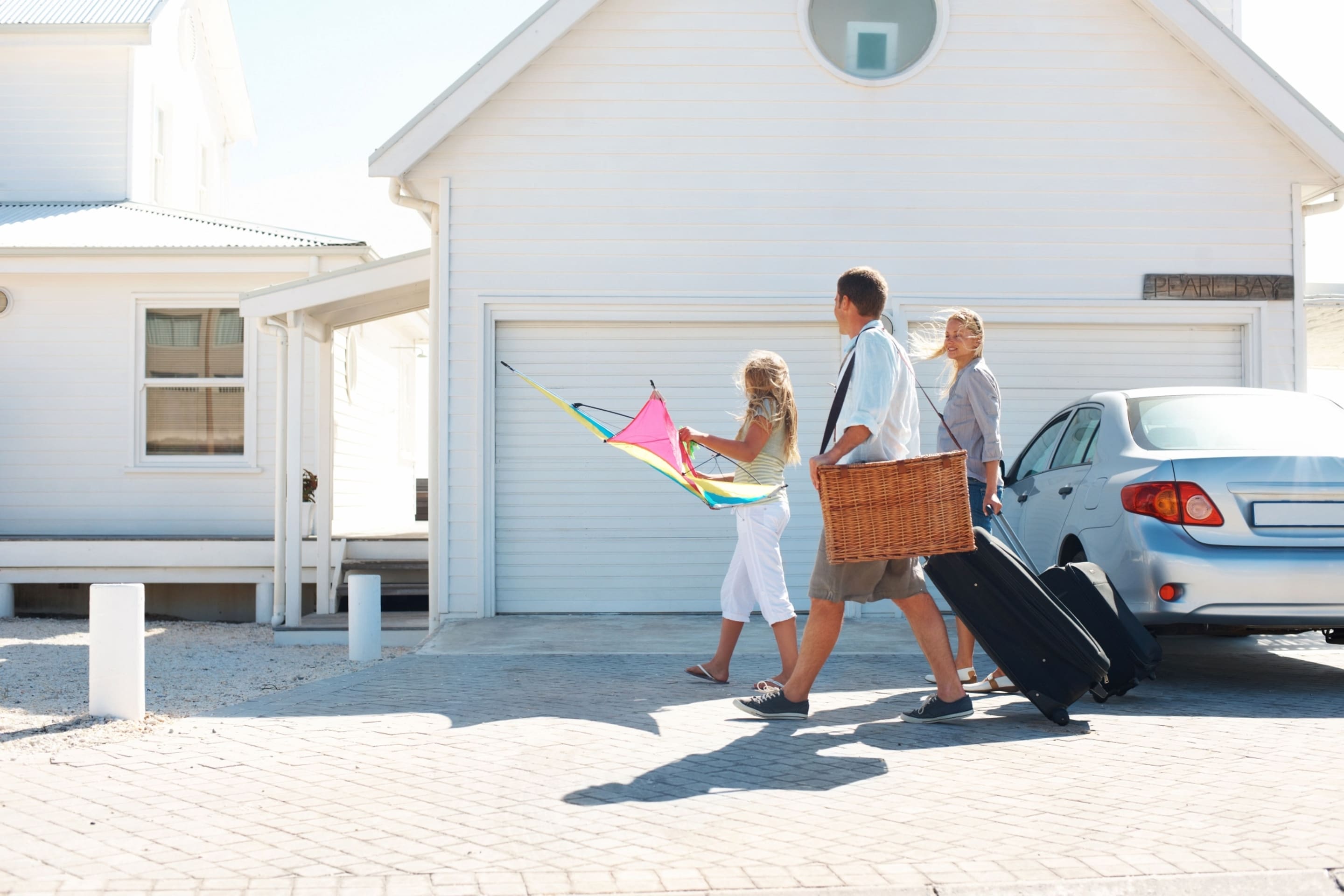 Family walking on a driveway toward a white house