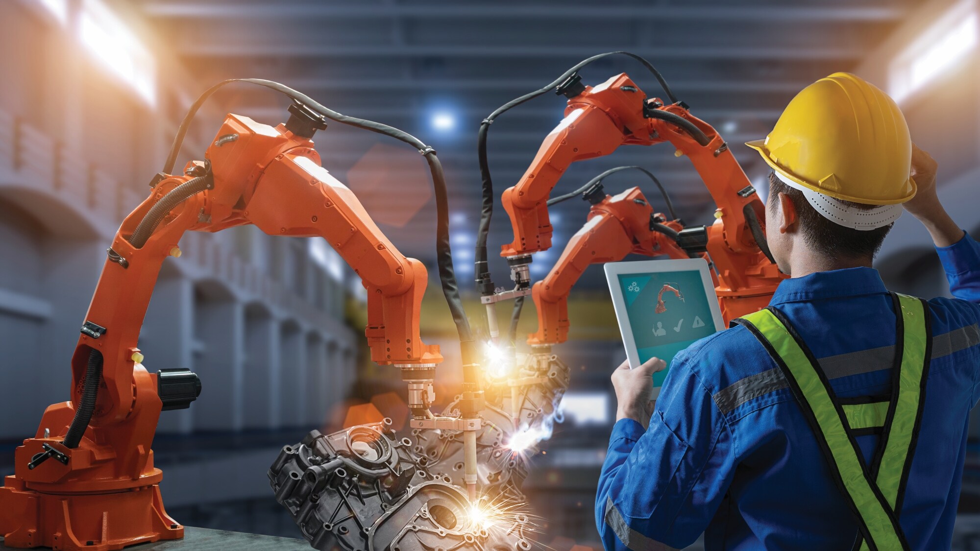 工厂内工程师使用平板电脑监控工业机械臂。