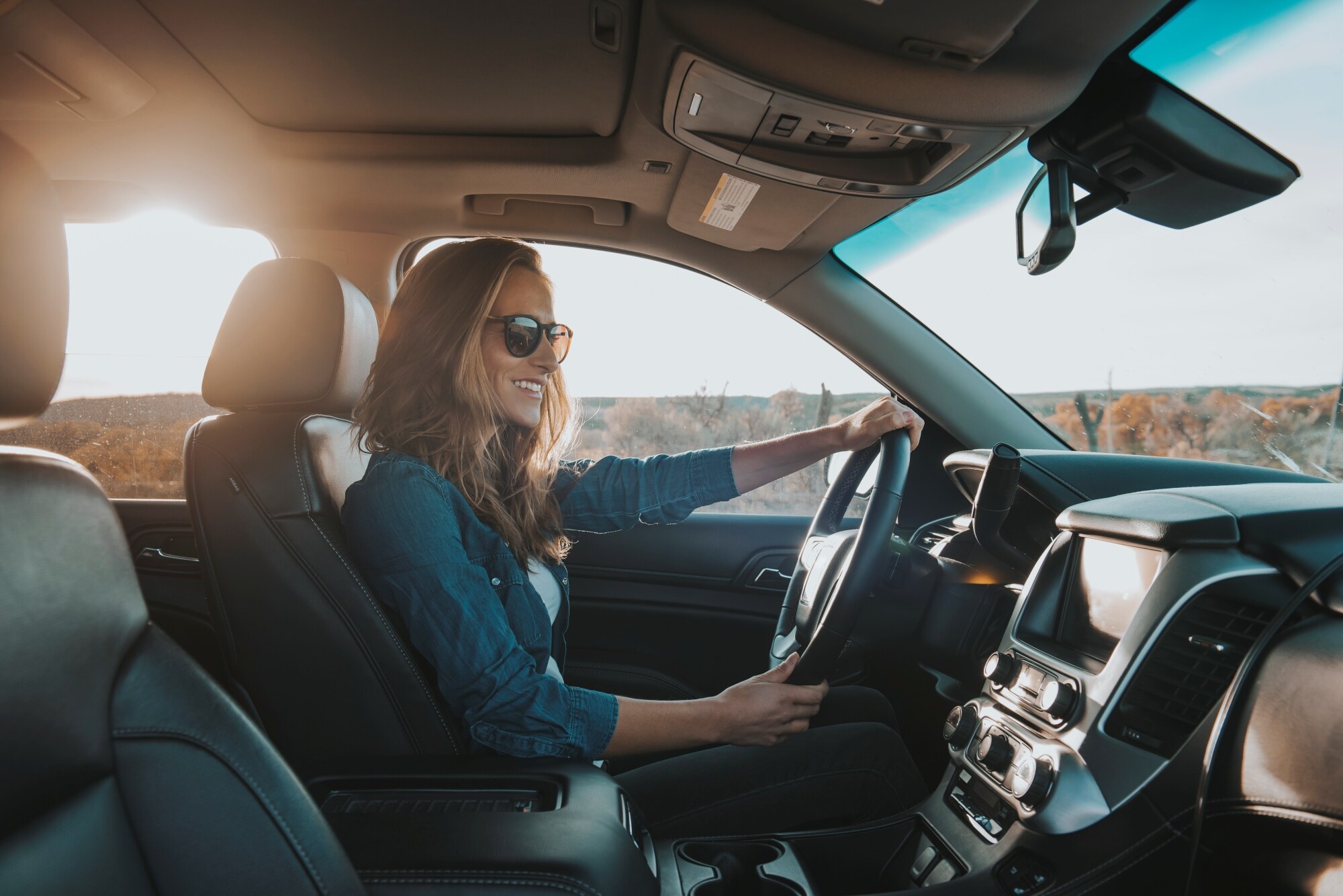 晴朗天气中驾车微笑的女士。