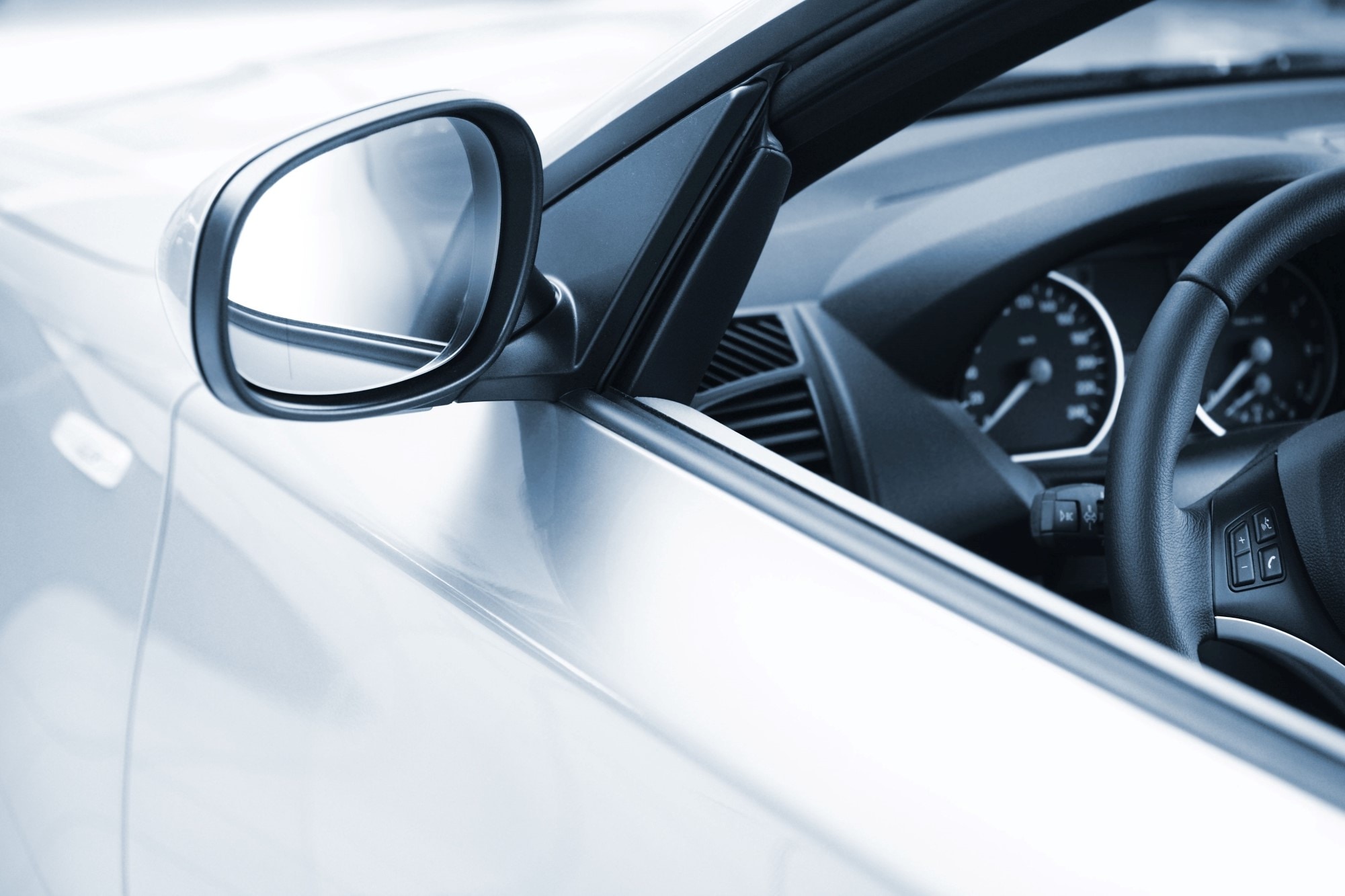 银色汽车后视镜特写及部分内饰仪表板，包括方向盘和仪表盘。